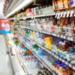 Different bottled and canned drinks arranged on a store shelf in a supermarket beverage aisle